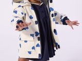 une petite fille en robe bleue et manteau blanc