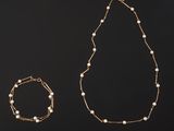 a gold necklace, bracelet and bracelet with pearls on a black background