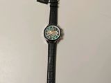 une image représentant une montre-bracelet avec un bracelet noir et un cadran vert