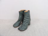 une paire de bottines en cuir vert posées sur une surface blanche