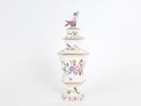 a white vase with a bird on top of it