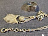 a silver bracelet and a silver ring on a table