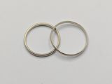 two silver wedding rings on a white surface