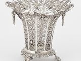 un vase en argent richement décoré, posé sur un socle, sur fond blanc