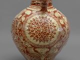 un vase orange et blanc posé sur une surface grise