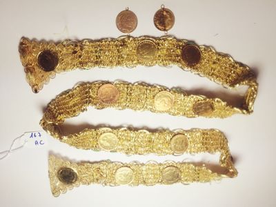 three gold bracelets and a coin on a white surface