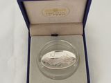 a silver coin in a blue box on a white surface