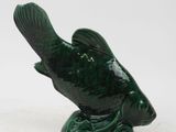 a small green fish statue on a white surface