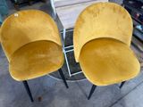 two yellow chairs sitting next to each other on top of a table
