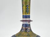 un vase bleu et vert posé sur une surface blanche