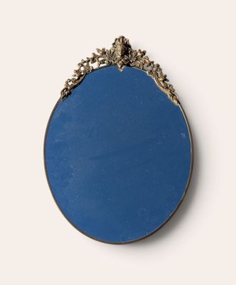 an oval mirror with a gold frame and a blue background