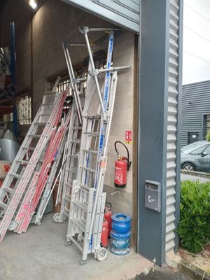 many ladders leaning up against the wall of a garage