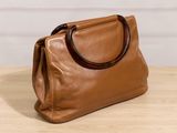 the brown leather handbag is sitting on a wooden table