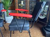 two black chairs and a table with a red top in a room