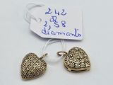 a close up of two gold heart charms on a white surface