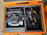 une mallette orange contenant des outils, posée par terre