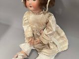 an antique doll sitting on the floor wearing a bonnet and dress