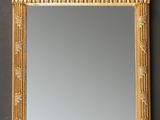 un miroir à cadre doré orné d'un motif décoratif, accroché au mur