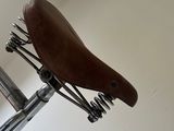 a brown leather seat on a bike that is attached to a wall