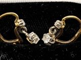 a pair of gold and diamond earrings in a black velvet case