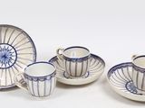 quatre tasses et soucoupes posées sur une table blanche