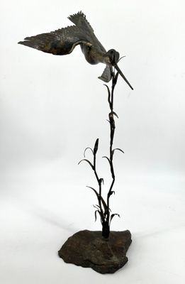 statue représentant un oiseau en plein vol au-dessus d'une plante, sur fond blanc