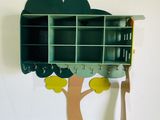 une étagère verte sur laquelle se trouve un arbre, à côté d'un mur blanc