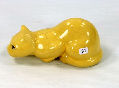 une figurine de chat jaune posée sur une surface blanche