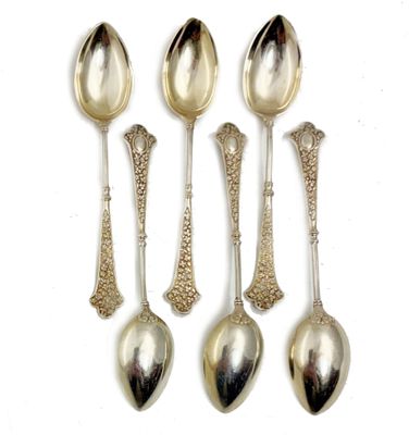 quatre cuillères en argent et deux cuillères en argent posées sur une surface blanche