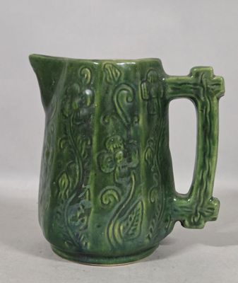 a green pitcher that has a handle on it