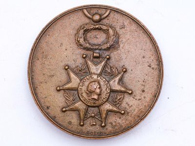 une médaille au revers d'une pièce de monnaie posée sur une surface blanche