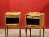 pair of bedside tables with drawers in front of a red wall