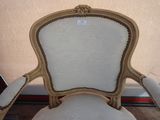 the back of a chair with a white upholstered seat and gold trim