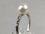 a white pearl and diamond ring on a clear surface