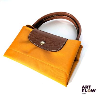 un petit sac à main avec une anse marron sur un fond blanc