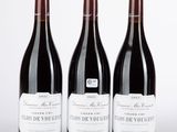 trois bouteilles de vin rouge posées sur une table blanche