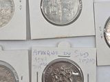 four different types of silver coins are on a white surface