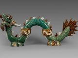 une paire de figurines de dragons verts et marron posées sur une surface grise