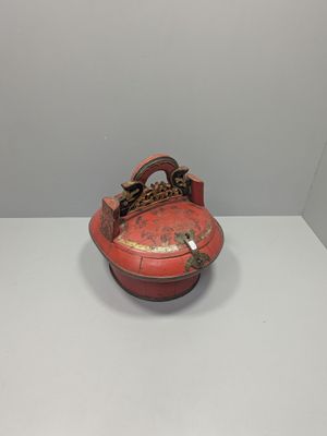 an old red box with a chain hanging from it on a white surface