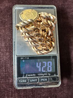 a gold chain on a scale with a coin on it
