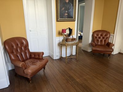 un fauteuil en cuir marron dans un salon où est accroché un tableau au mur