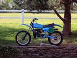 a blue dirt bike parked in front of a white fence