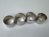 four silver cups sitting next to each other on a white surface