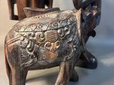 two figurines of elephants and a man sitting on a chair