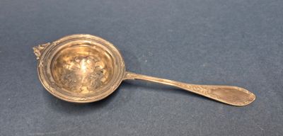 une cuillère ancienne en argent avec un manche, posée sur un fond bleu