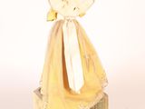 a small doll with a yellow dress and a white umbrella