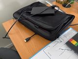 a laptop computer sitting on top of a desk next to a bag