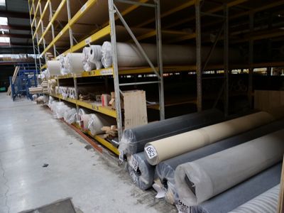 many rolls of fabric on the shelves in the warehouse