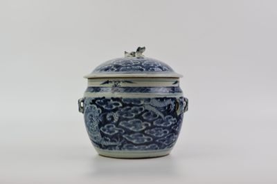 un vase bleu et blanc muni d'un couvercle, posé sur une surface blanche