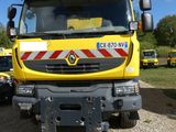 un camion jaune garé sur la terre battue